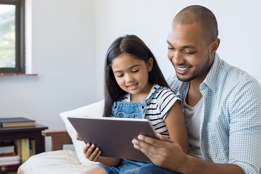 Blog - Father and Daughter Using a Tablet Together While Sitting on the Sofa